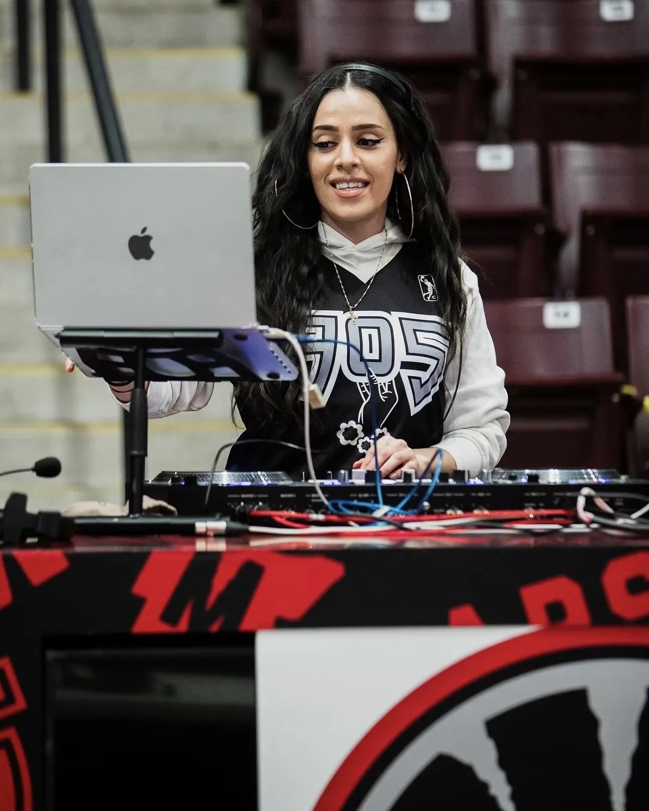 DEEJAY T-JR. smiling at her laptop behind the Raptors 905 DJ booth before tip-off.